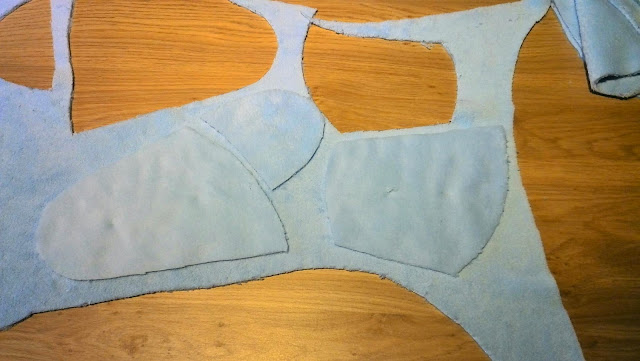 Alle geknipte fleece onderdelen van het babyslaapzakje uitgespreid op de vloer