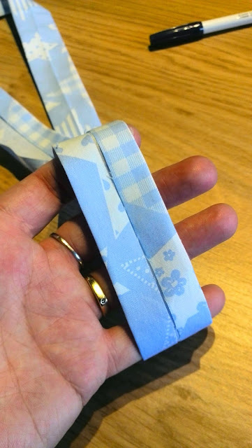 Hand houdt gevouwen biaislint in blauwe sterren-en-hartjesstof