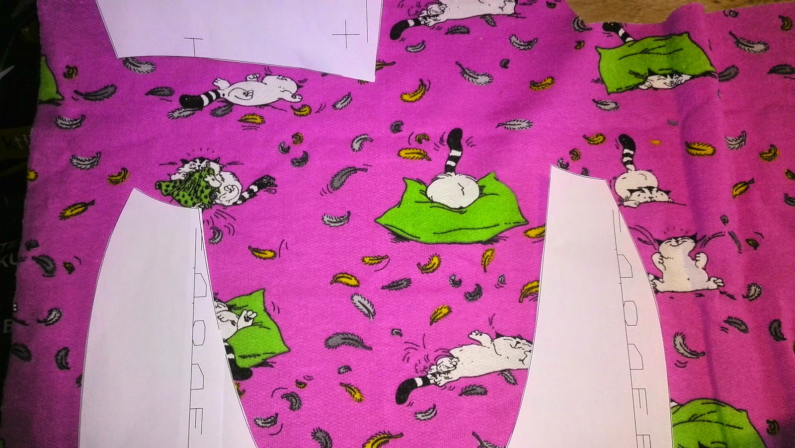 Felroze rekstof met grappige figuren waarop patroononderdelen zijn uitgelegd voor de hoodie