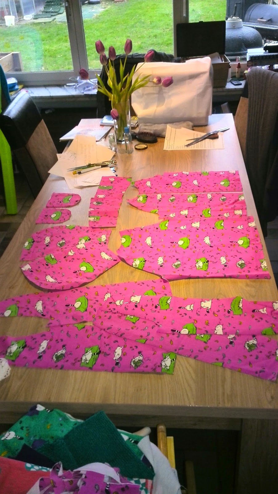 Alle geknipte stukken van de hoodie uitgespreid op de naaitafel: voorpand, achterpand, mouwen en kap