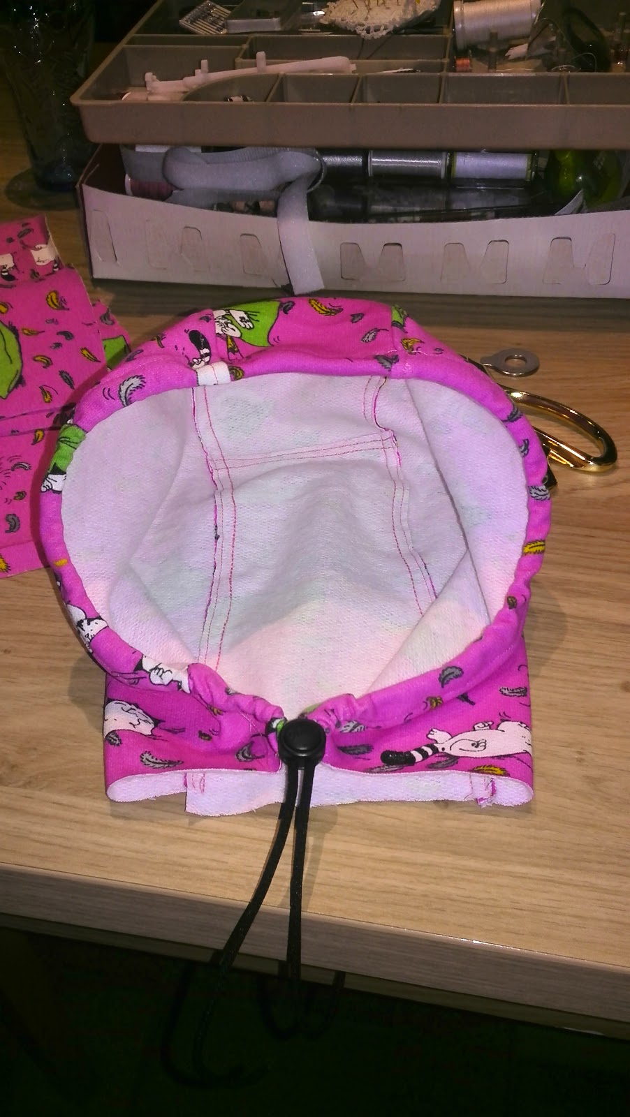 Het afgewerkte kapje van de hoodie met lila voering, koordjes en zwarte koordstop