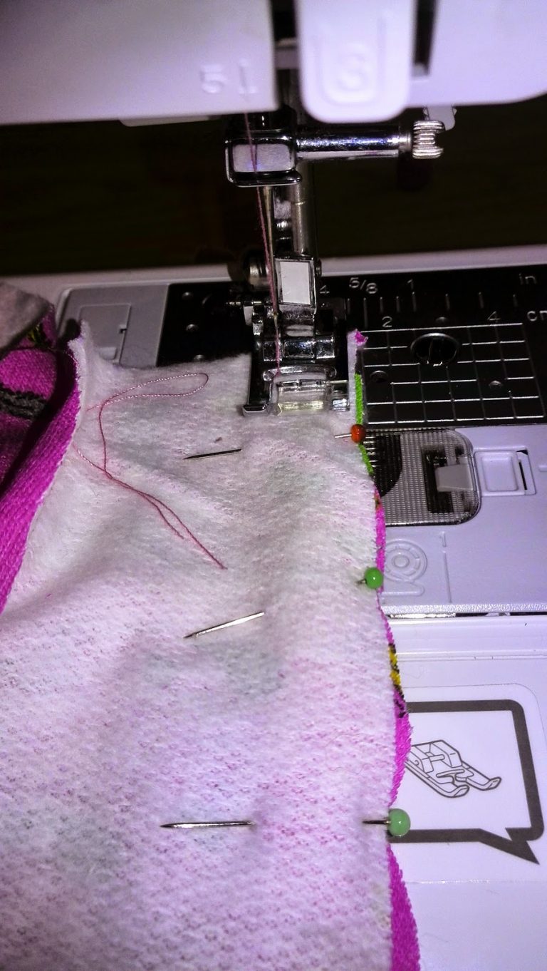 Close-up van naaimachine tijdens het naaien van de hoodie, roze stof onder de naaivoet