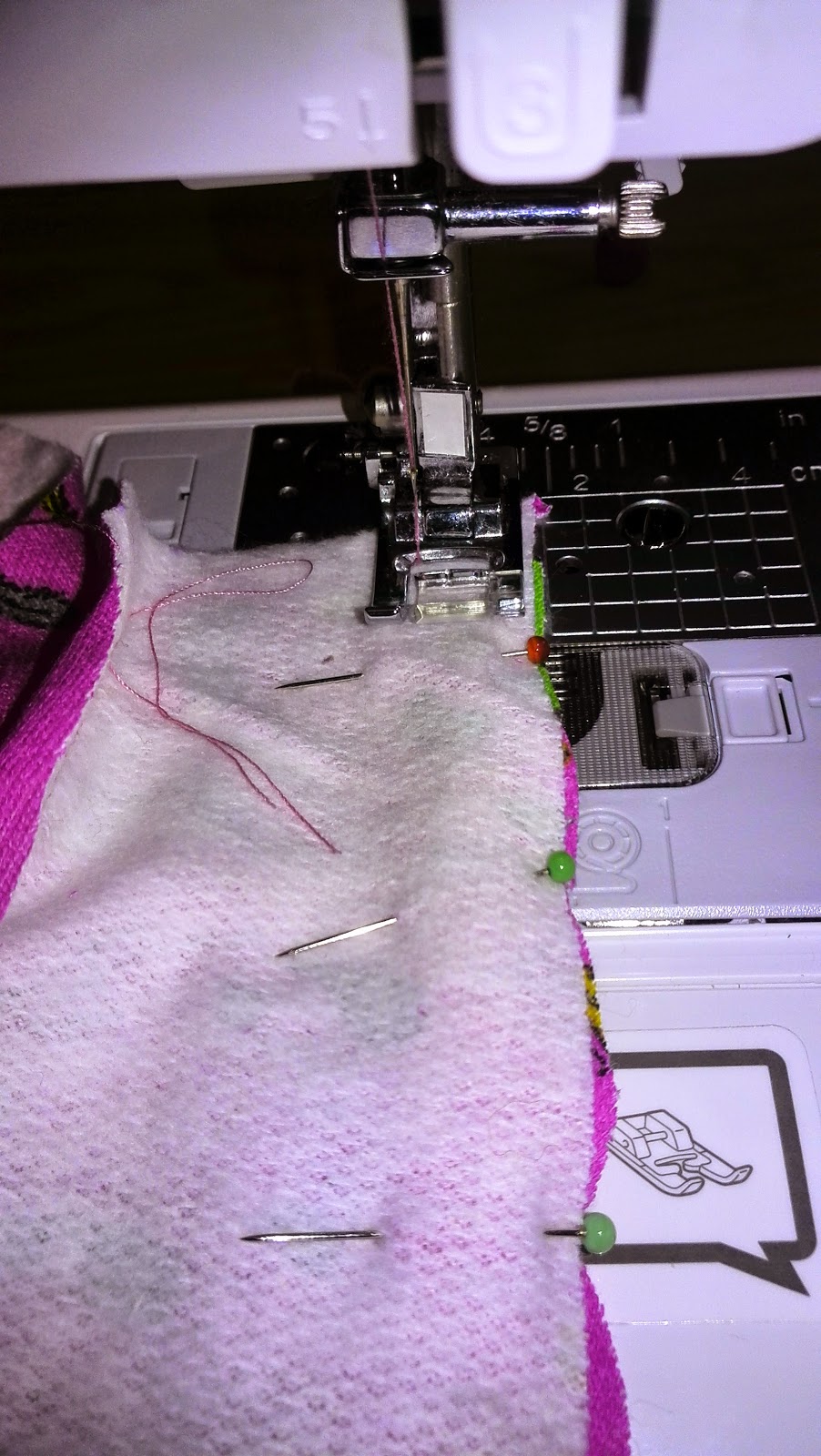 Close-up van naaimachine tijdens het naaien van de hoodie, roze stof onder de naaivoet