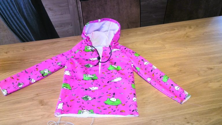 Volledig afgewerkte roze hoodie met kap, plat neergelegd op houten tafel