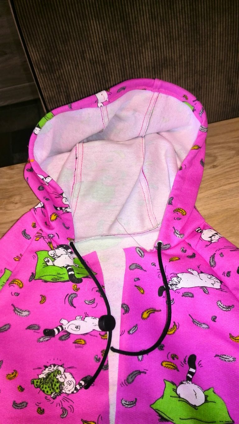 Binnenkant van de kap van de hoodie met lila voering en koordjes zichtbaar