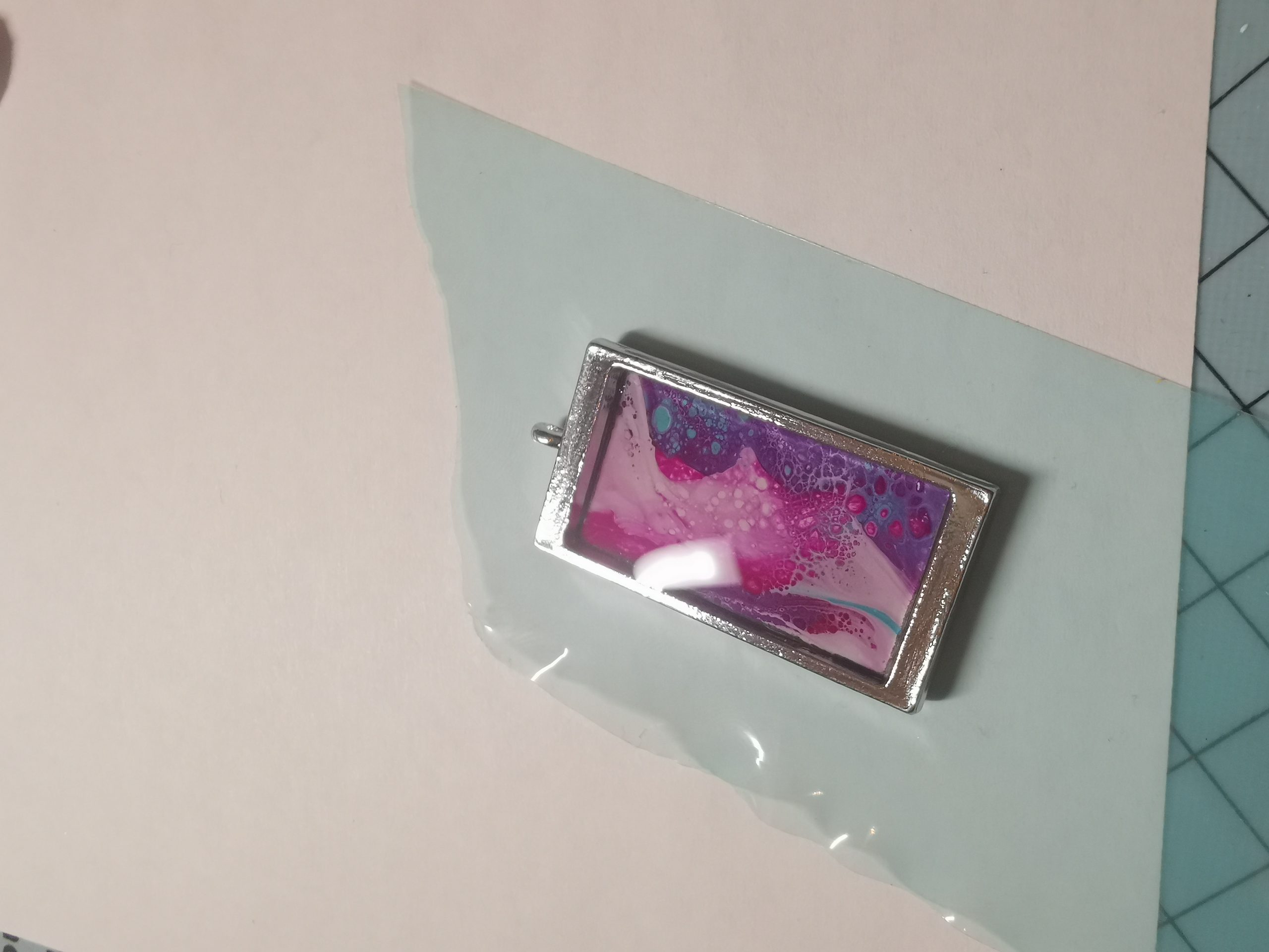Fluid-art insert in pendant frame with UV resin over it