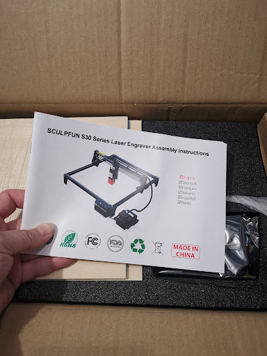 Handleiding en onderdelen van de Sculpfun S30 Pro tijdens het uitpakken.