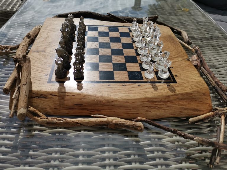 Afgewerkt eiken schaakbord met zwarte epoxy ruiten, glazen schaakstukken en drijfhouttakjes als decoratie