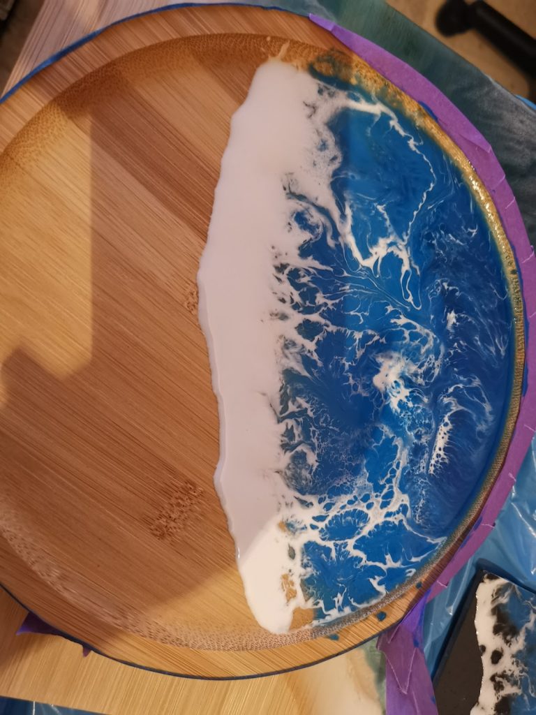 Ronde bamboe tapasplank met blauw-witte oceaan epoxy in wording, nog in de mal