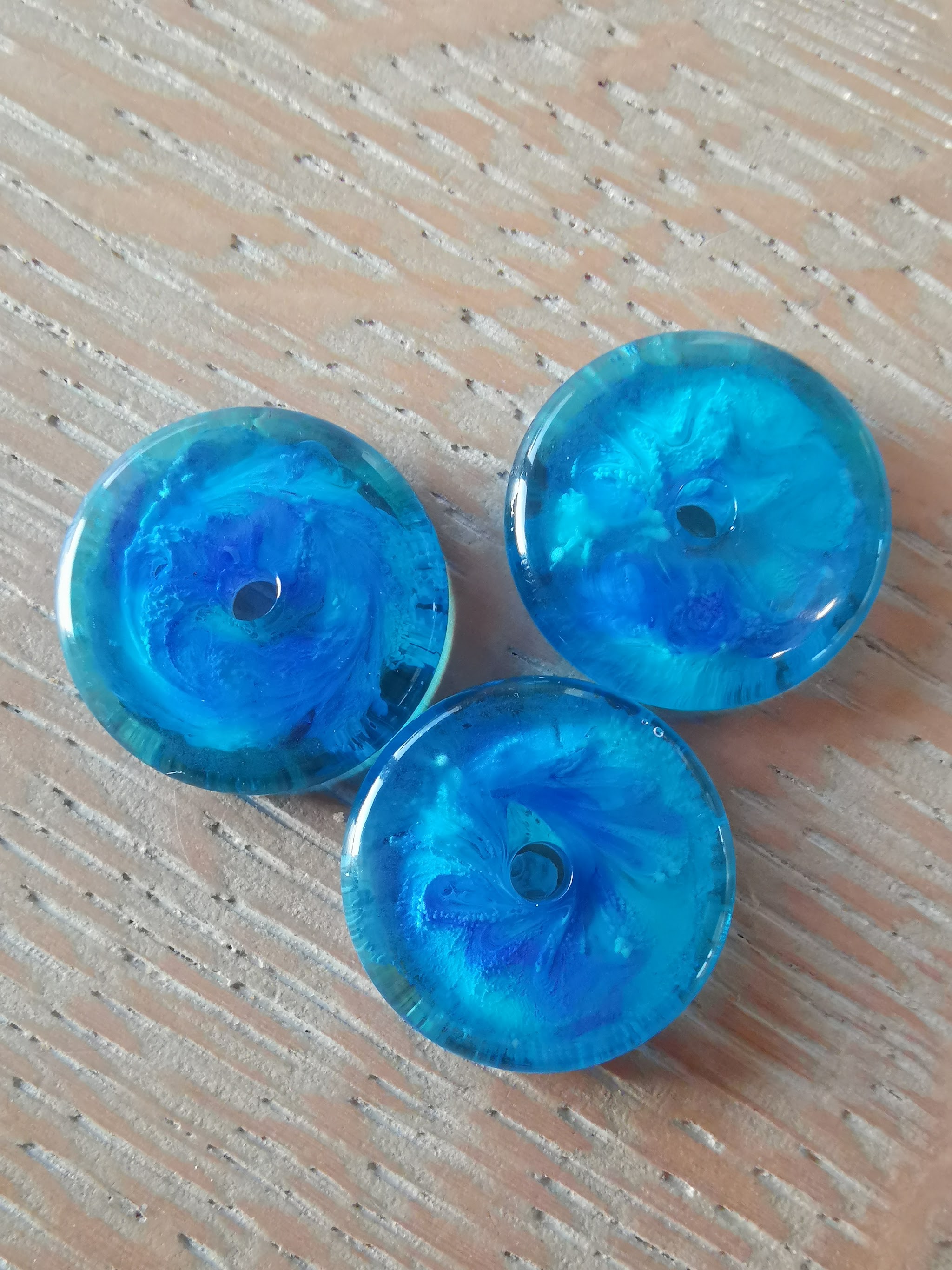 Drie blauwe en teal resin donuts gemaakt van de restjes hars na het gieten van de hairpins