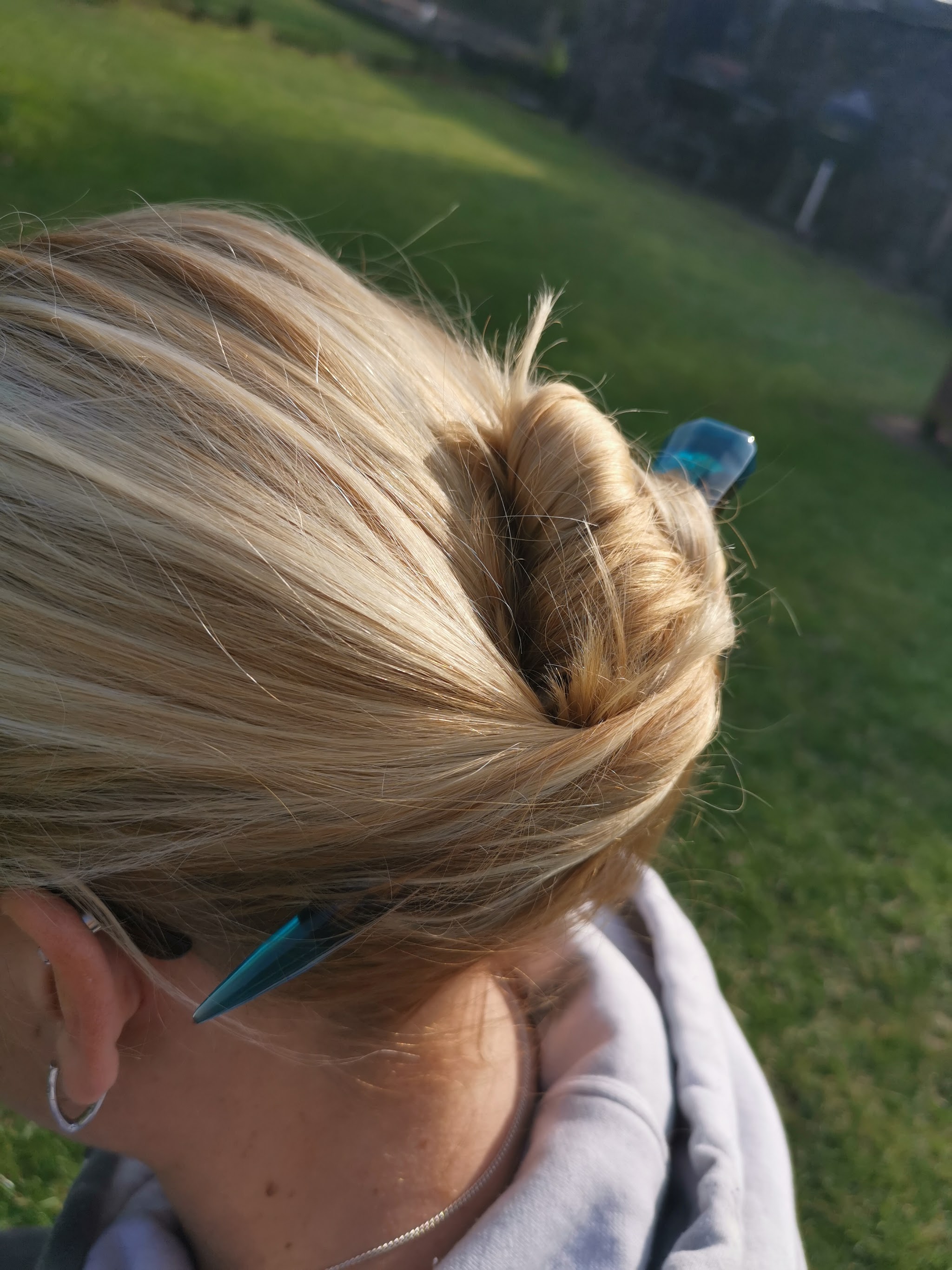 Drijfhout en resin hairpin gedragen in opgestoken wrong, van achteraan gezien in gouden avondlicht — beide uiteinden van de hairpin zijn zichtbaar