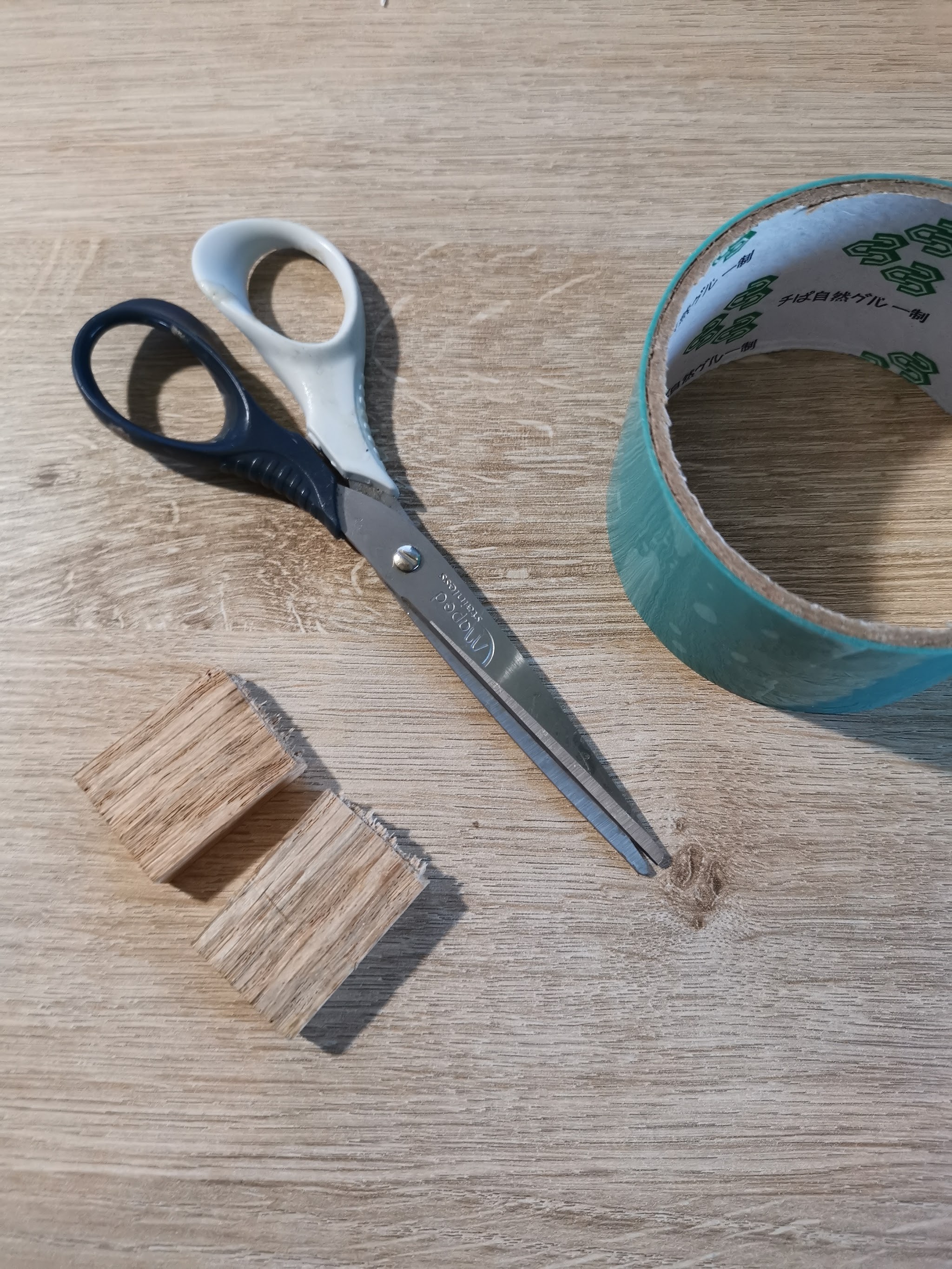 Gebroken eikblokje met ruwe breukrand, naast resintape en schaar — alles klaar om mallen te maken