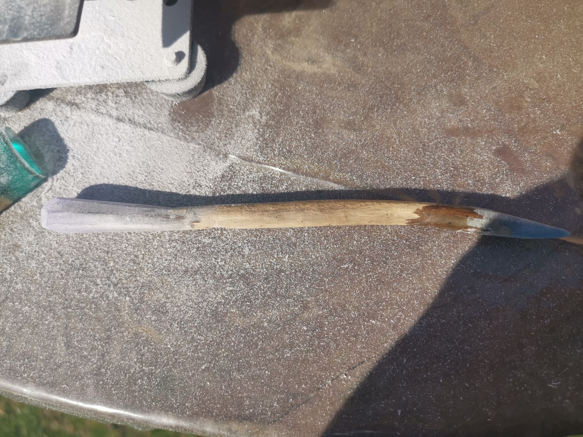 Drijfhout hairpin na het schuren, liggend naast de mini bandschuurmachine — de resin is mat maar de punt en uiteinden hebben hun definitieve vorm gekregen