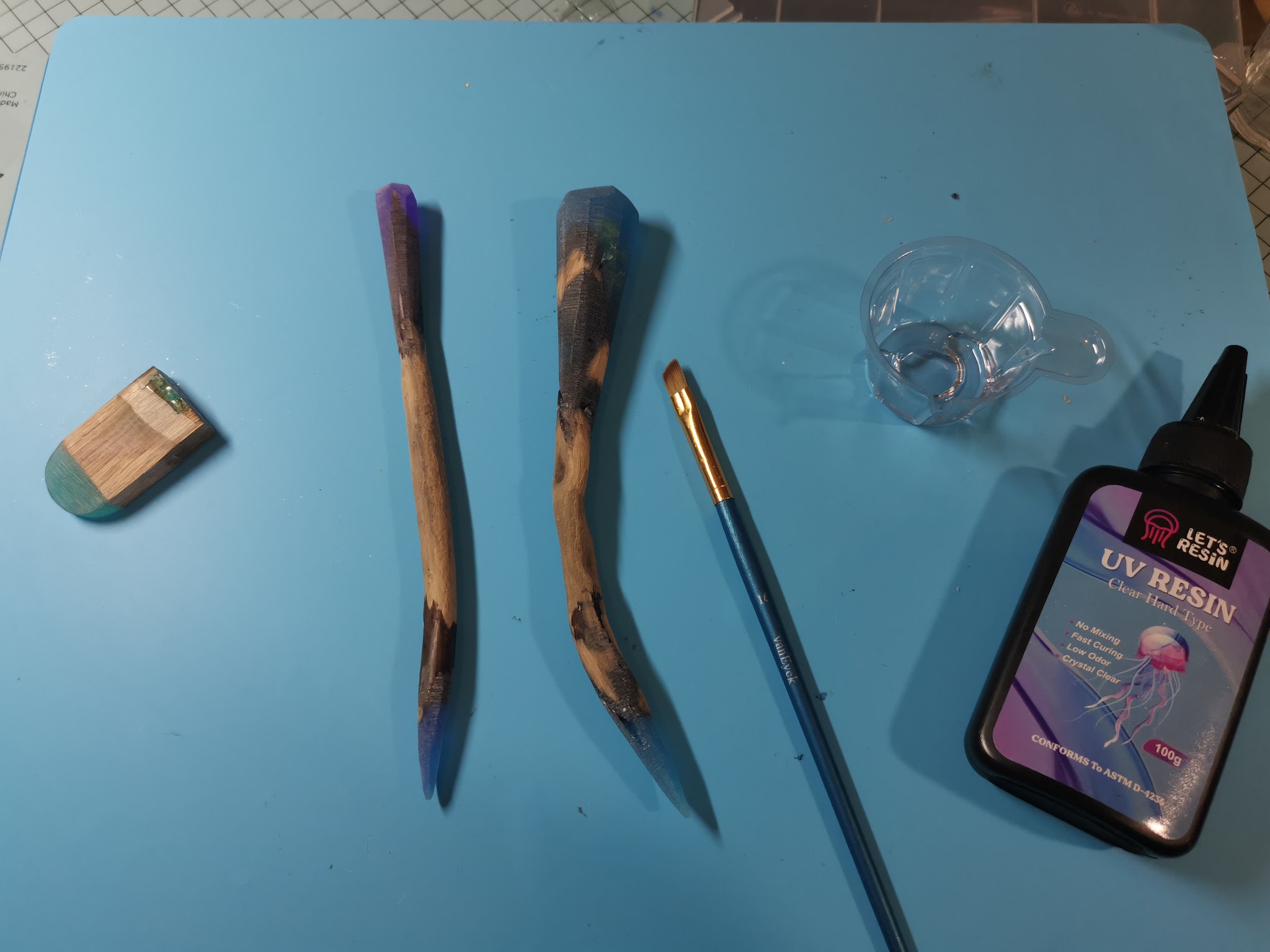 UV-hars wordt laagje voor laagje met een klein kwastje aangebracht op de resin-uiteinden van een drijfhout hairpin