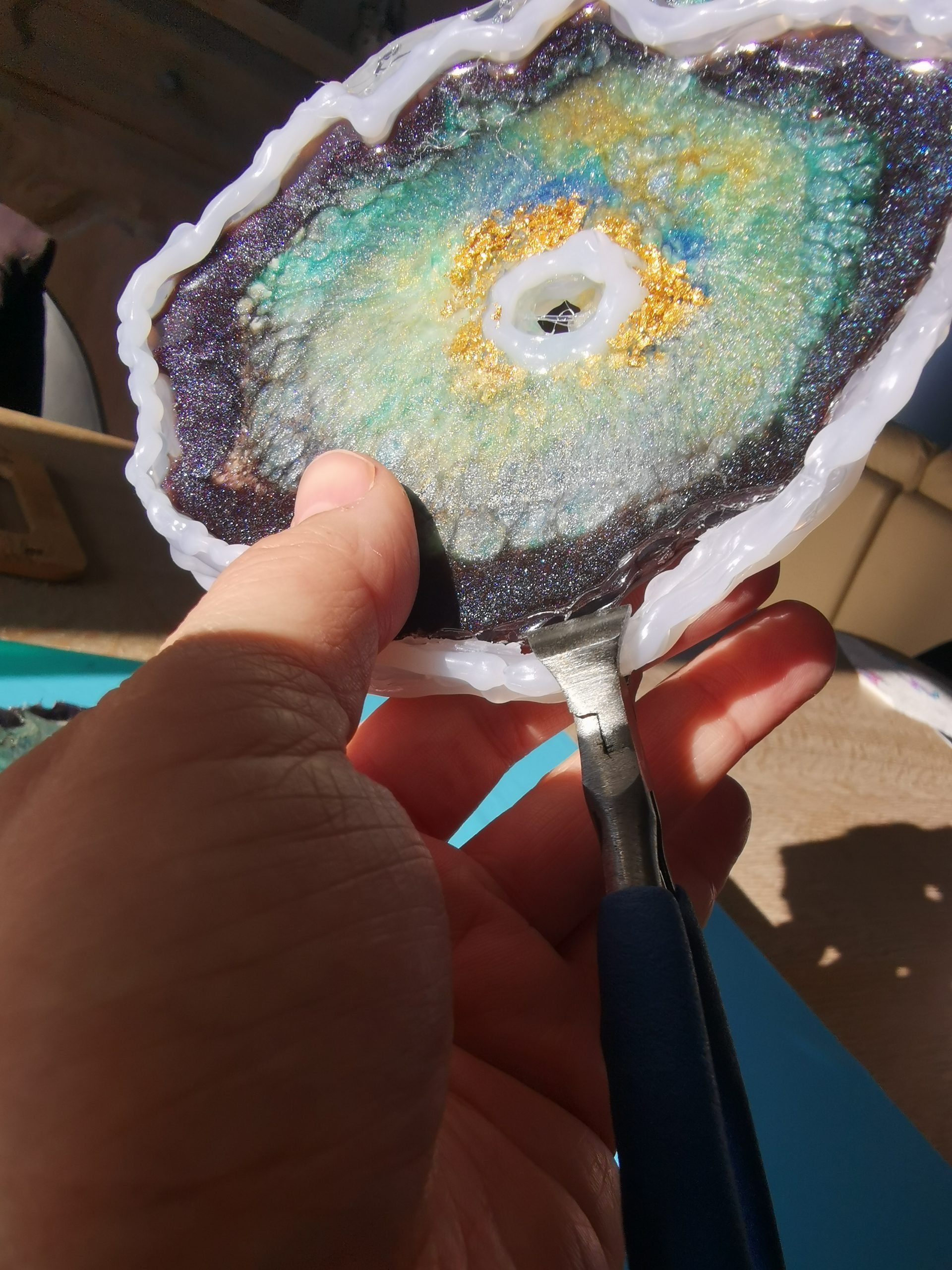 Met een tang proberen de hotlijmrand te verwijderen — de lijm zit muurvast aan de resin