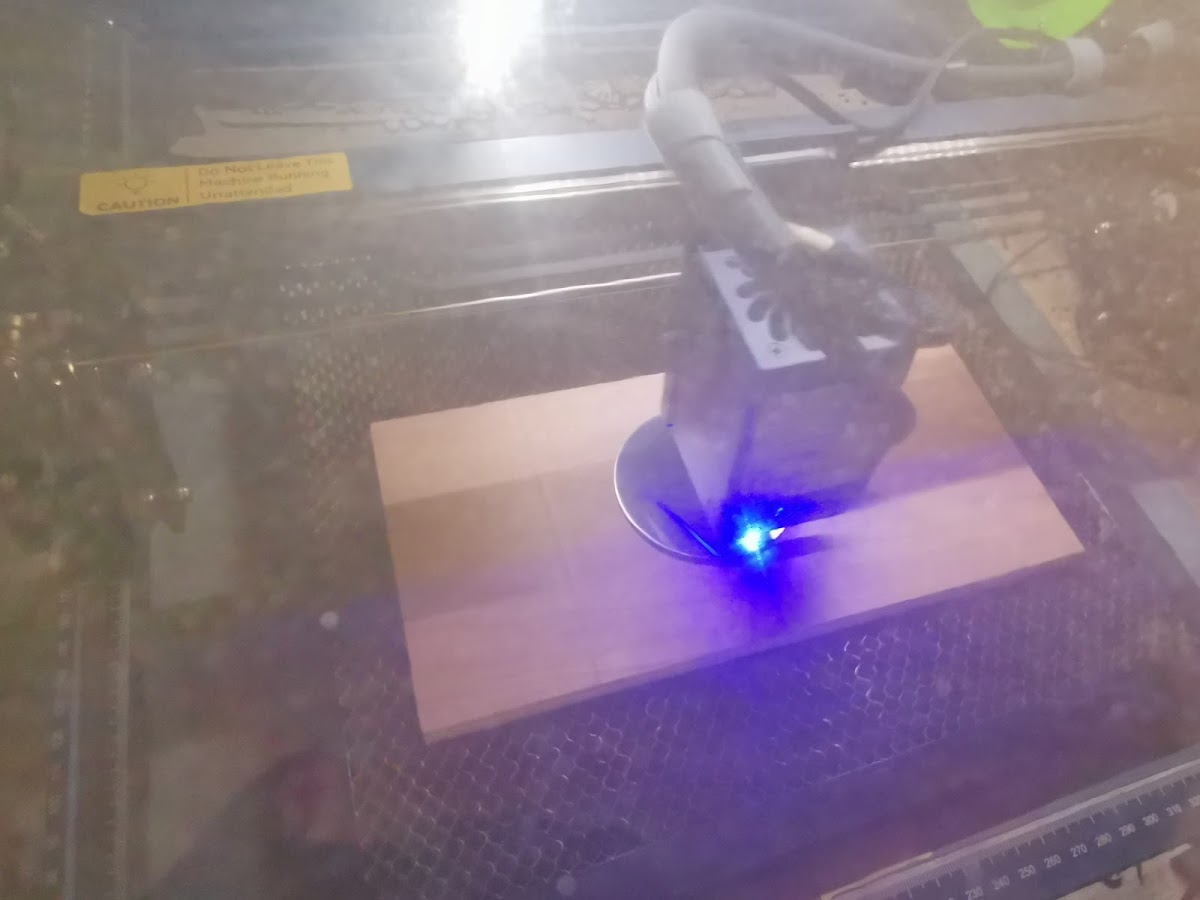 Blauw laserlicht zichtbaar tijdens het graveren van de coaster door de beschermkap heen