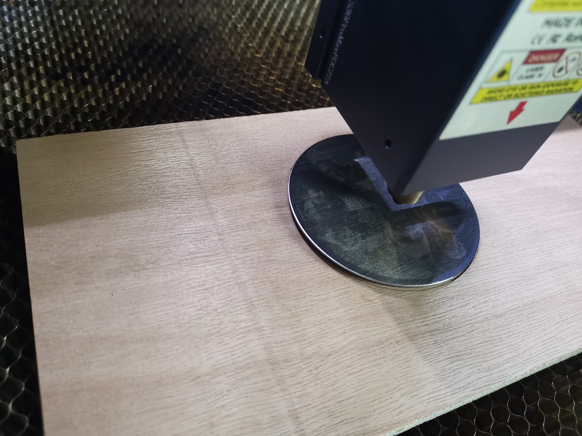 Roestvrijstalen coaster geplaatst in de ingegraveerde cirkelmal op multiplex, van bovenaf gezien