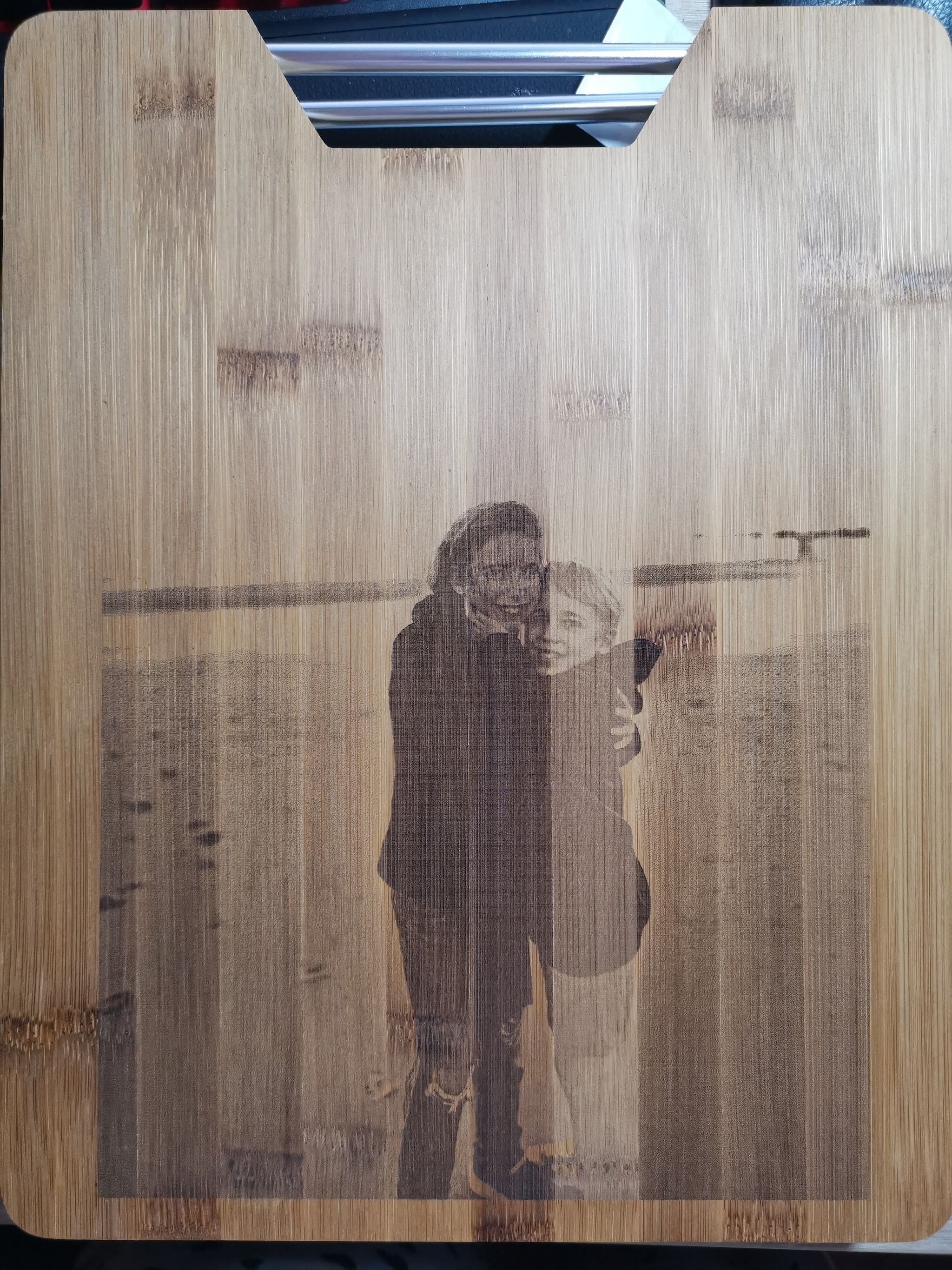 Bamboe snijplank met handgreep, bovenaanzicht, met een gedetailleerde gegraveerde portretfoto van twee personen