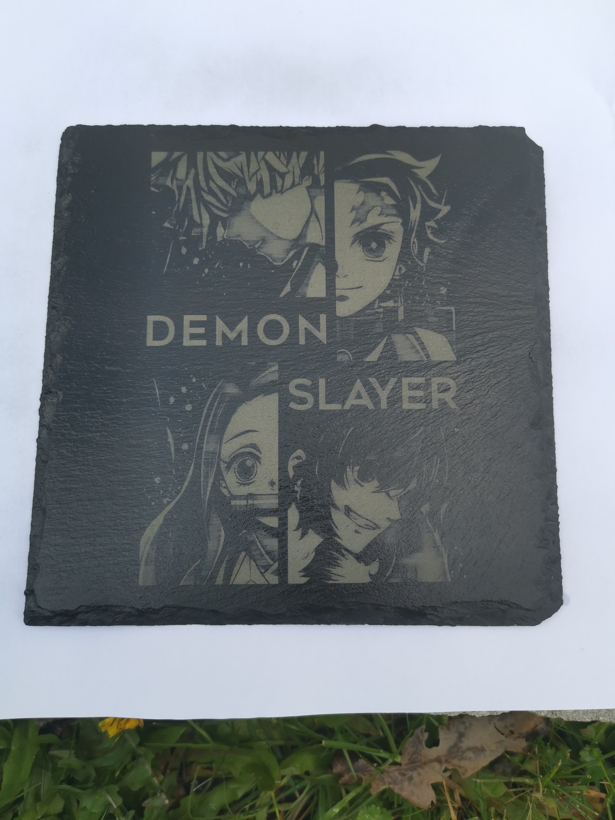 Donkere leistenen vierkante coaster met gegraveerde Demon Slayer tekst en vier anime karakterportretten in kwadranten