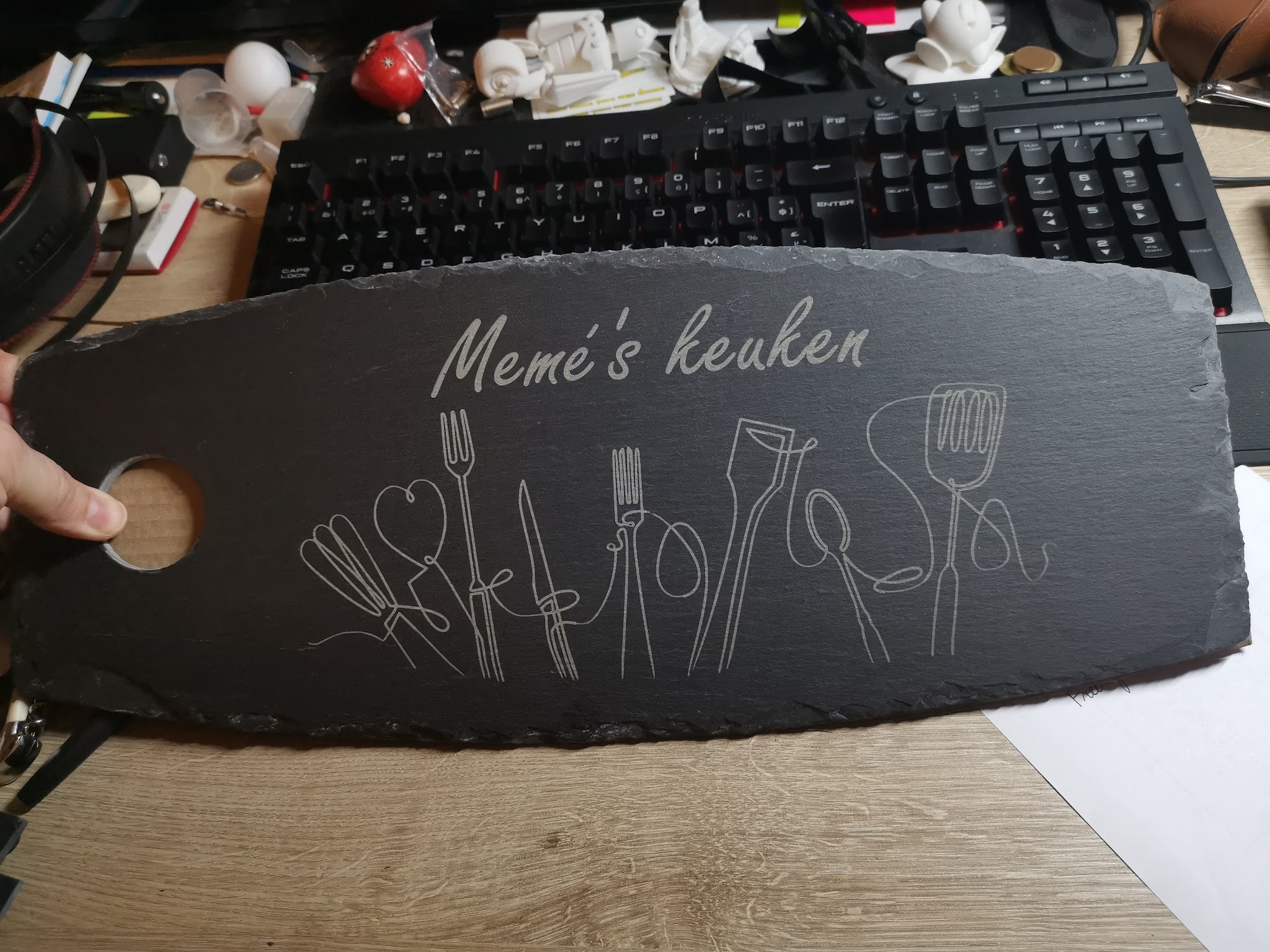 Leistenen plank met gegraveerde tekst Mémé's keuken en handgetekende keukengerei zoals vorken spatels en lepels