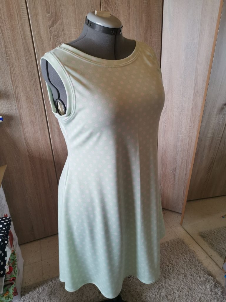 Mintgroene jersey jurk met roze stippen — halslijn en armsgaten afgewerkt met coverlock.