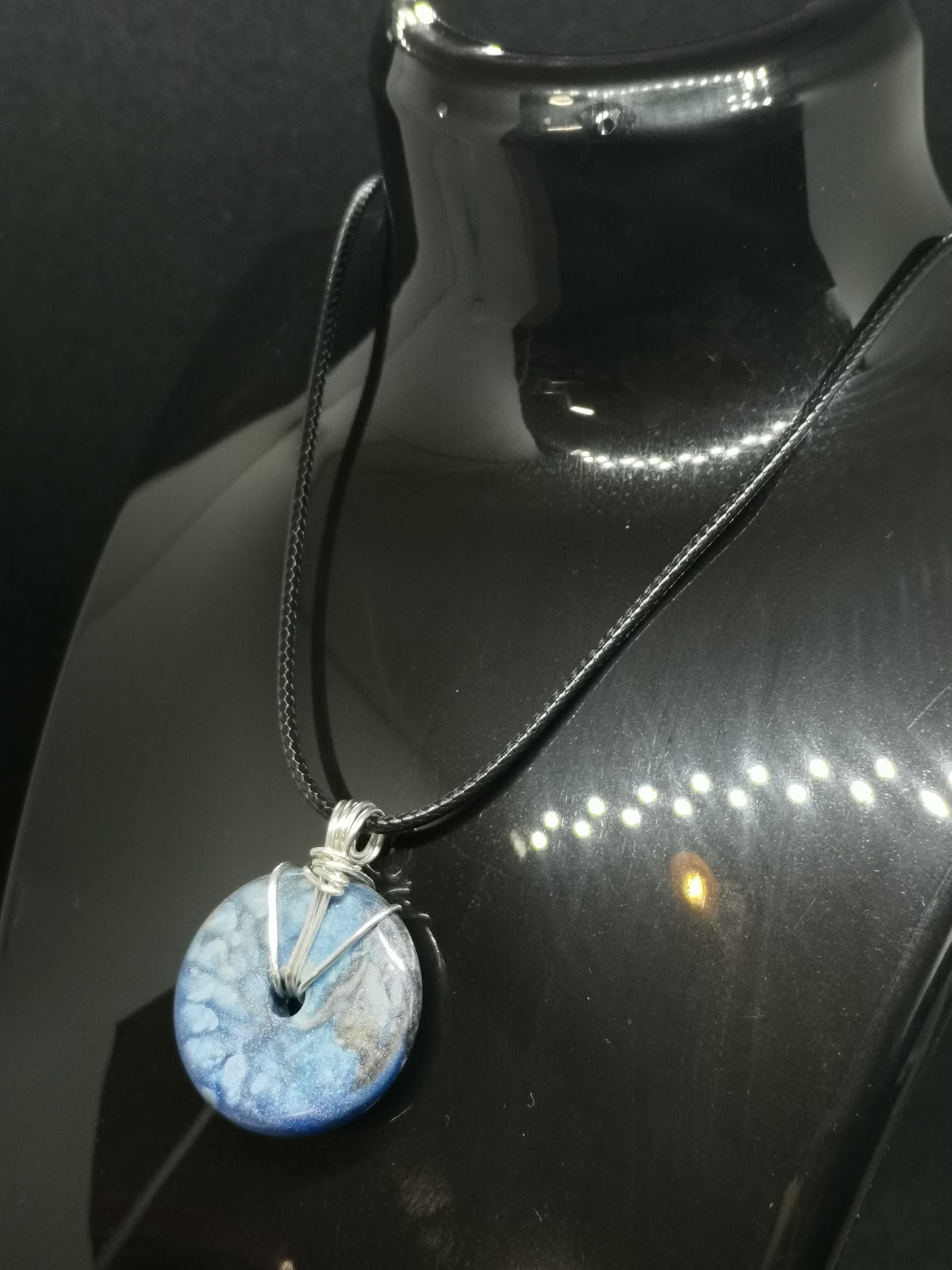 Necklace on bust: black cord with blue marble donut bead wrapped in silver wire