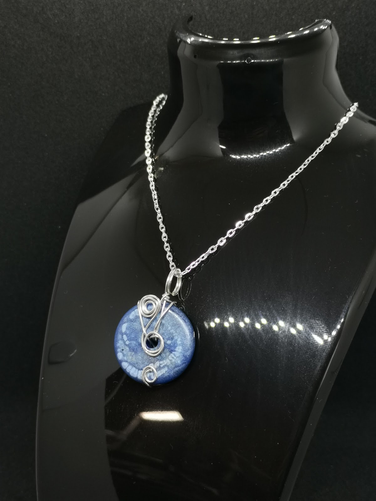 Necklace on bust: silver chain with blue donut bead and decorative wire wrap with spirals