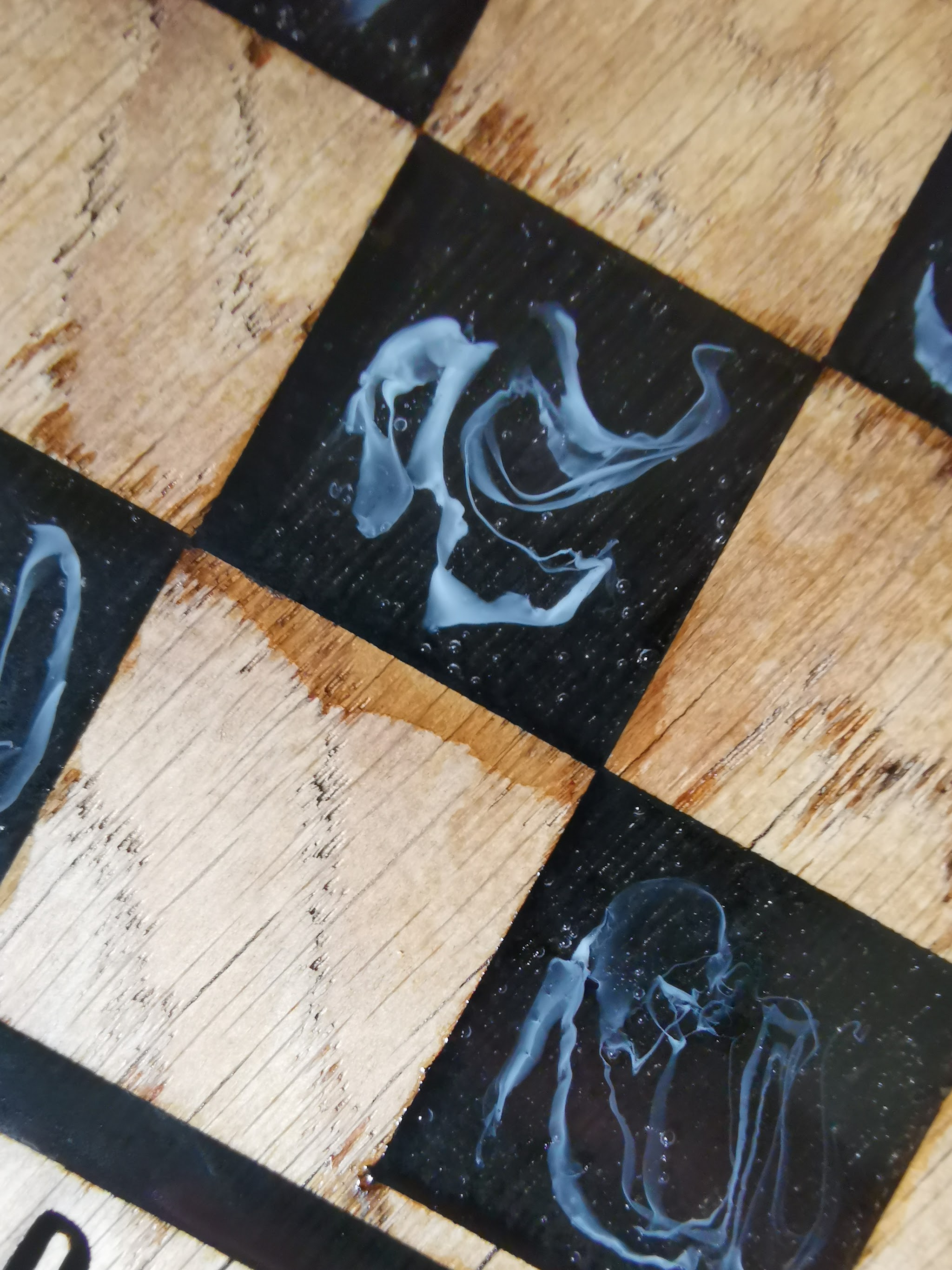 Witte resin dye sliertjes in heldere epoxy die een rookpatroon creëren met de spuit