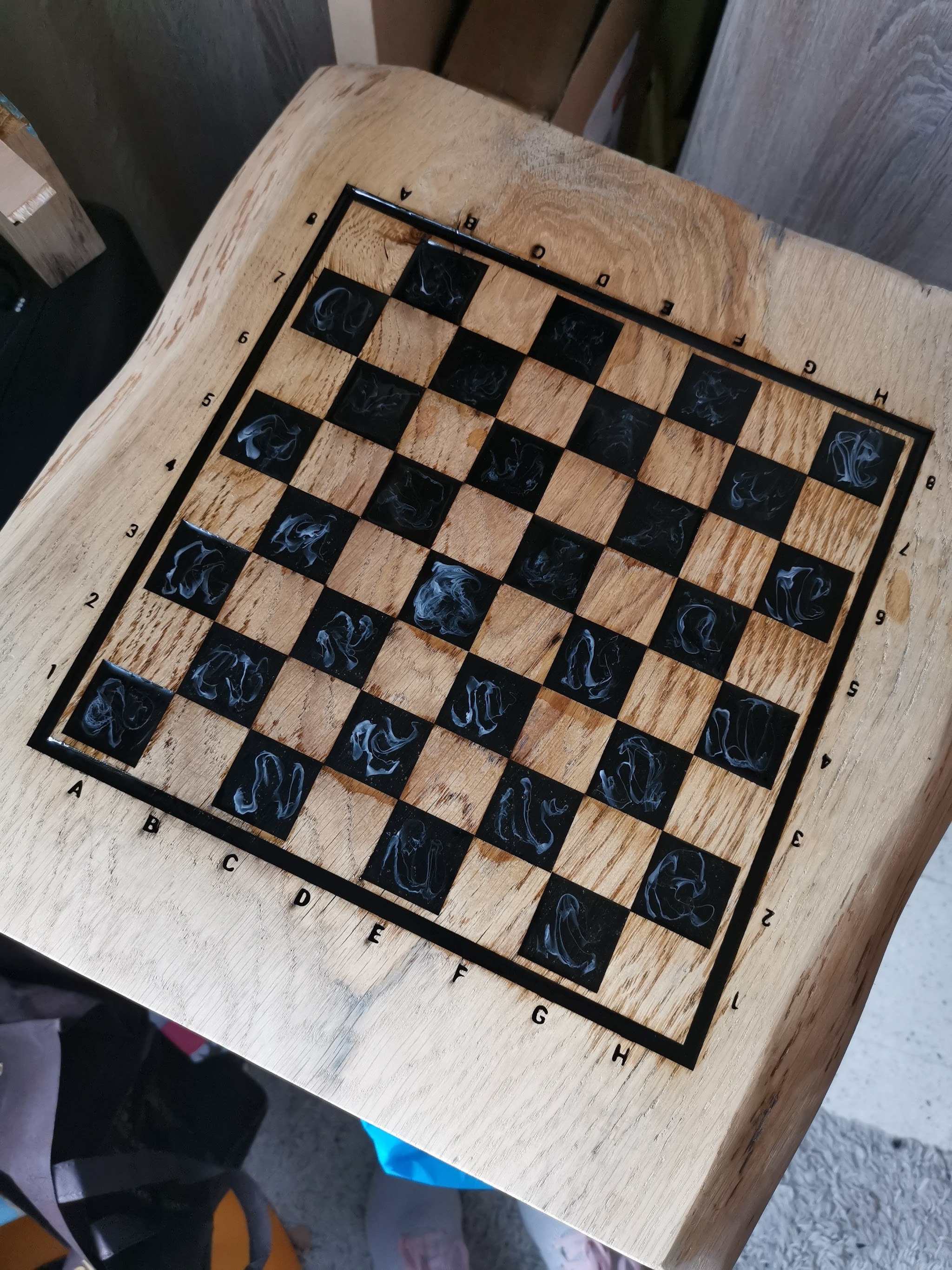 Heldere epoxy voorzichtig gieten in de lasergebrande vakjes van het eiken schaakbord