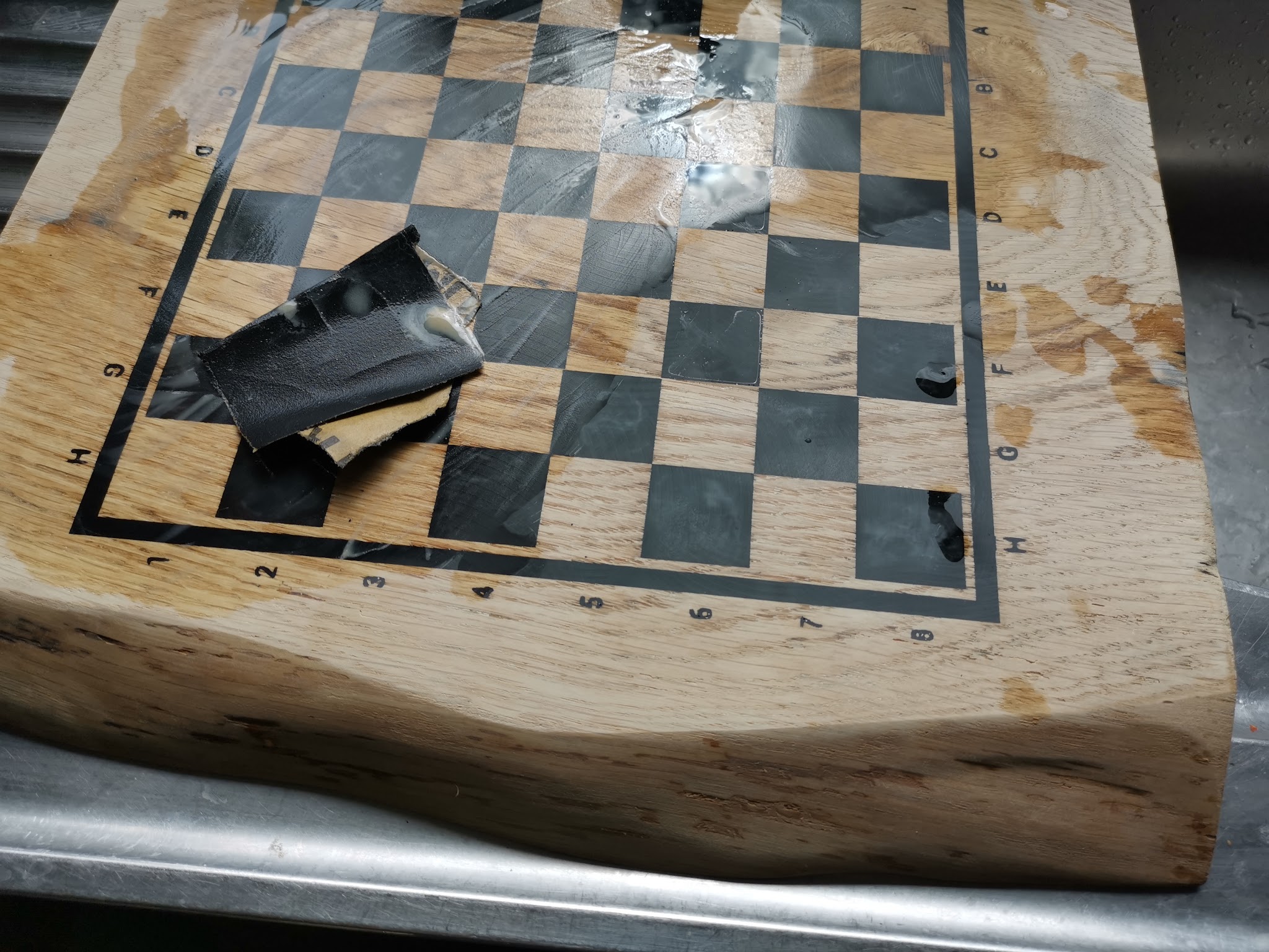 Natschuurfase van epoxy schaakbord met zwart schuurblok en water op het oppervlak