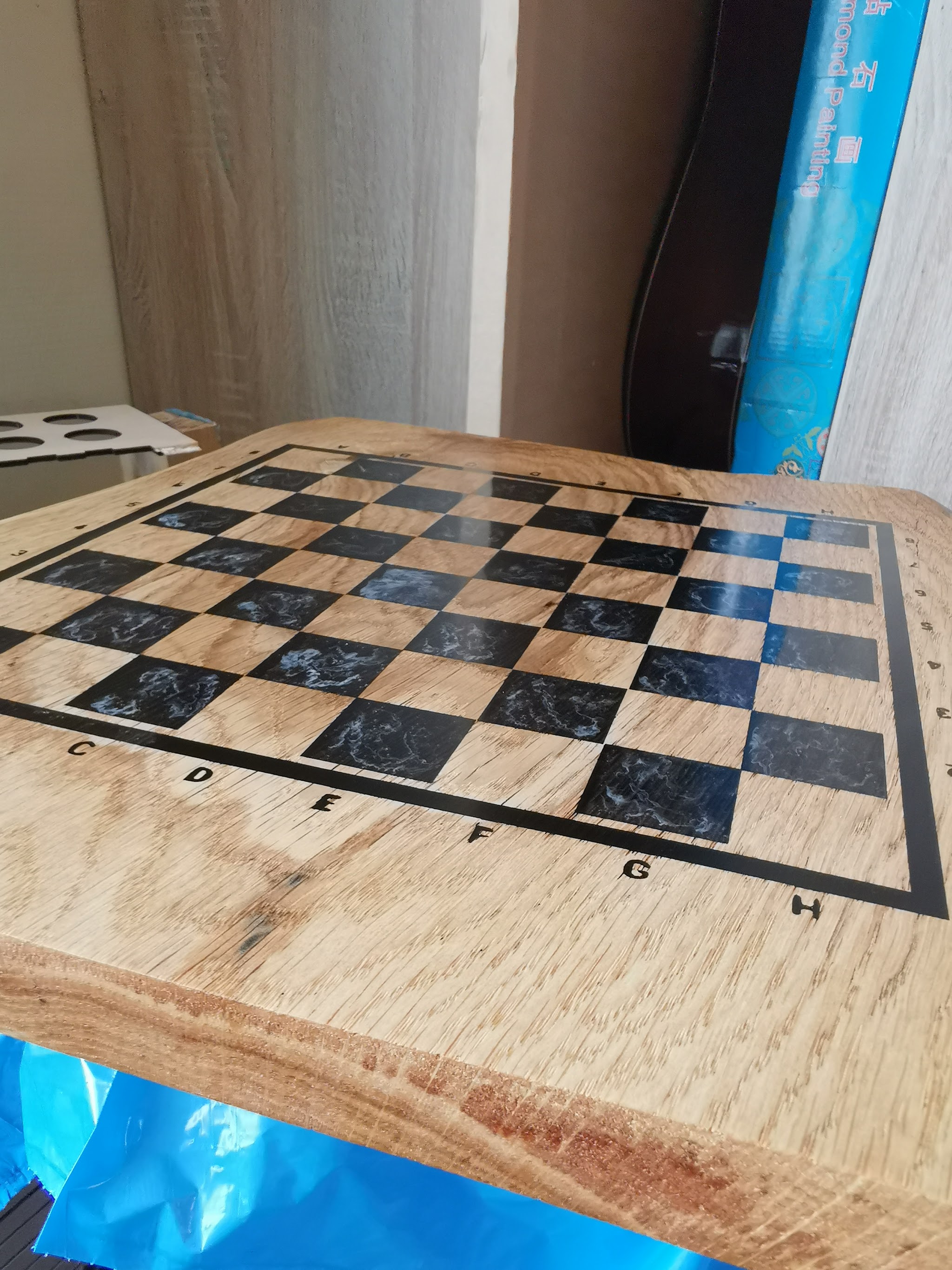 Vogelperspectief van voltooid schaakbord met 8x8 epoxy vakjes met rookeffect en eiken vakjes met gegraveerde coordinaten