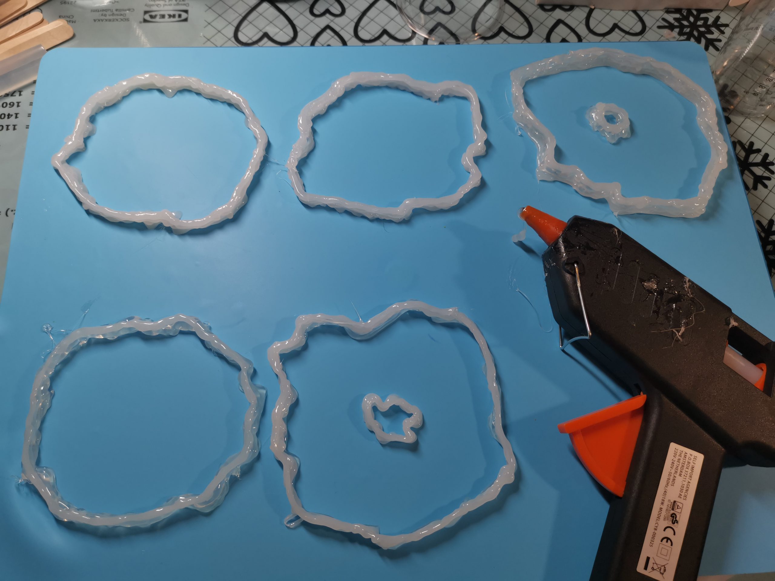 Hotlijmpistool met de vijf vers gespoten freeform mallen op de siliconenmat, klaar voor het gieten