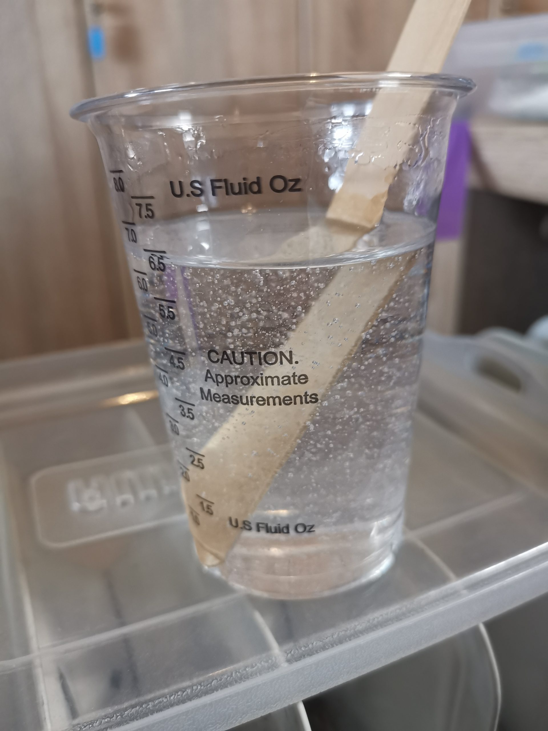 Transparante maatbeker met helder gemengde gietepoxy — klaar om te verdelen over de kleurbekers