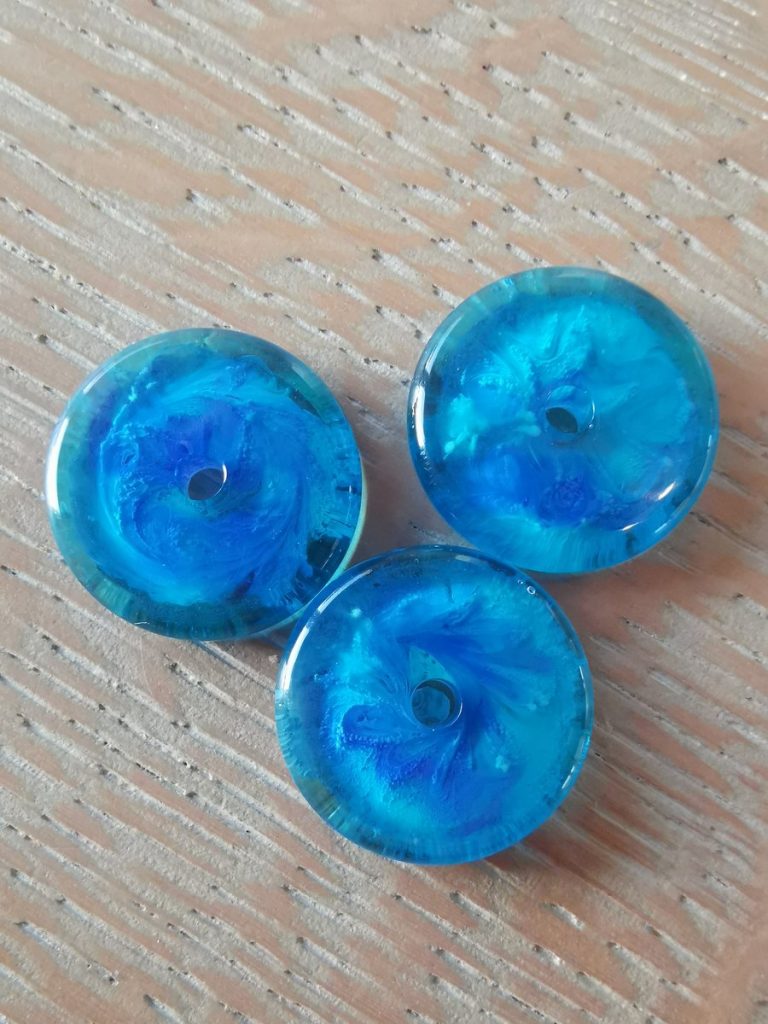De drie afgewerkte blauwe harsdonuts — elk met zijn eigen unieke patroon