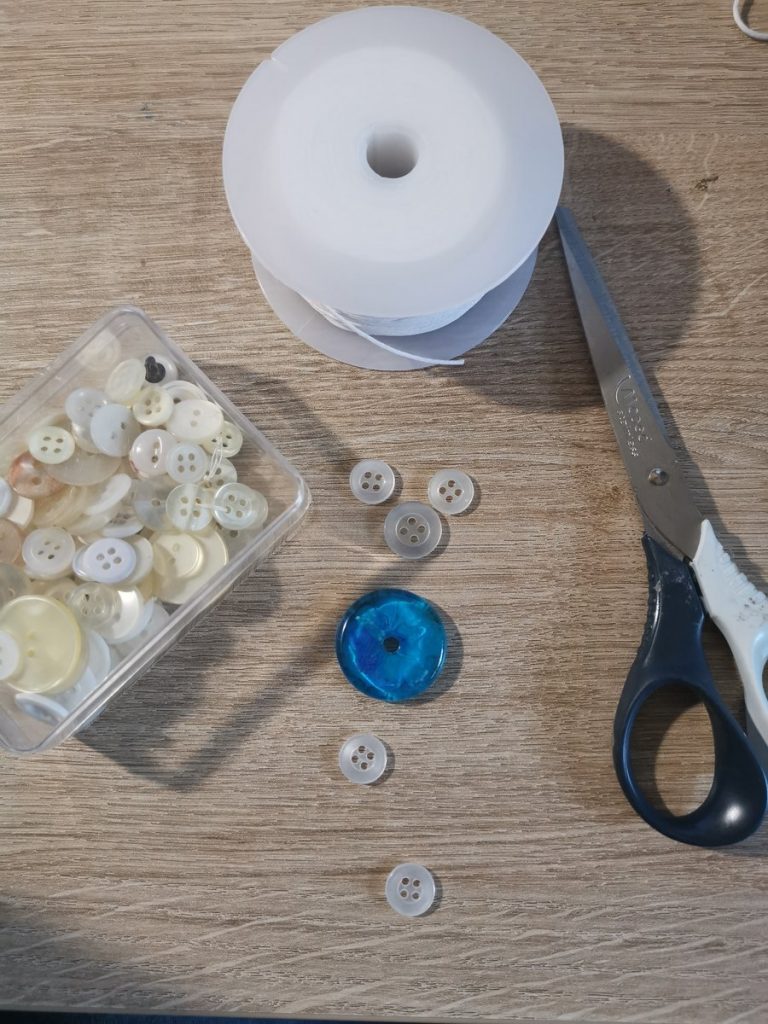 Alles klaargelegd: knopen in verschillende maten, wit koord, schaar en de harsdonut