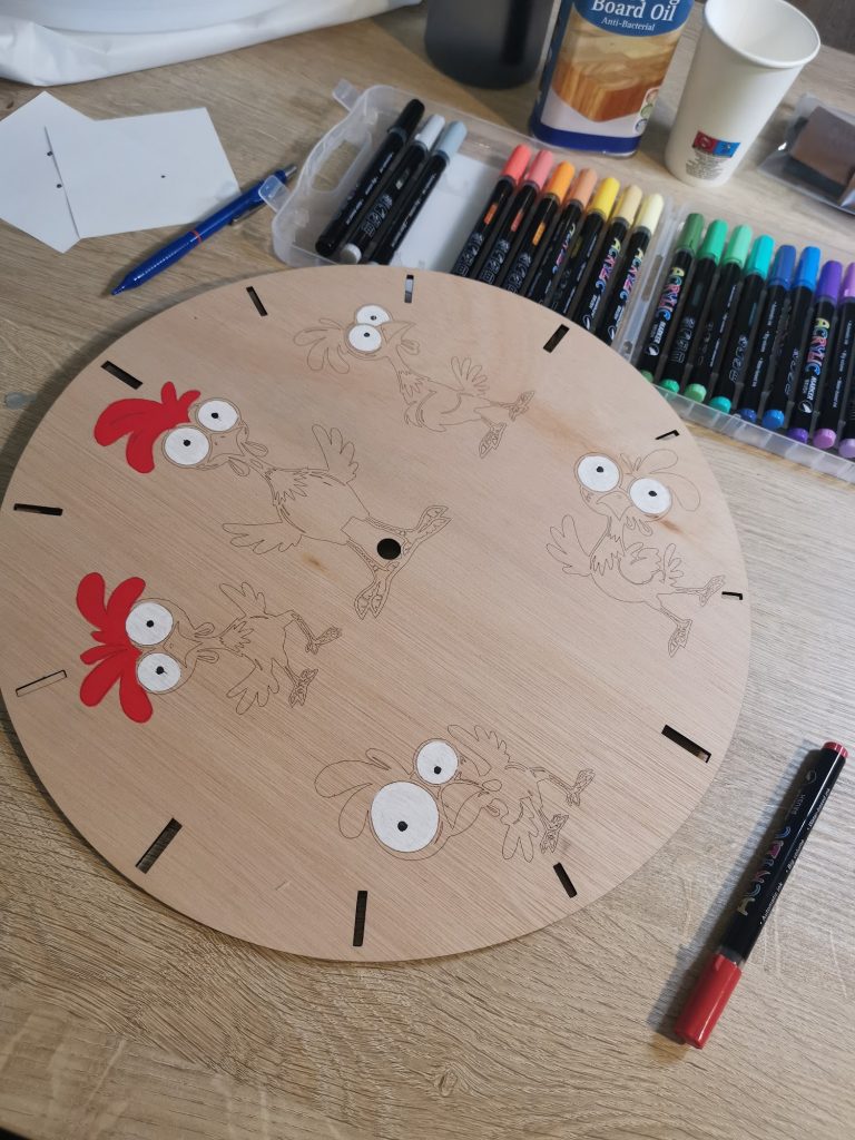 Werktafel met acrylstiften, fineliners en board oil klaar om de kippenklok te beschilderen