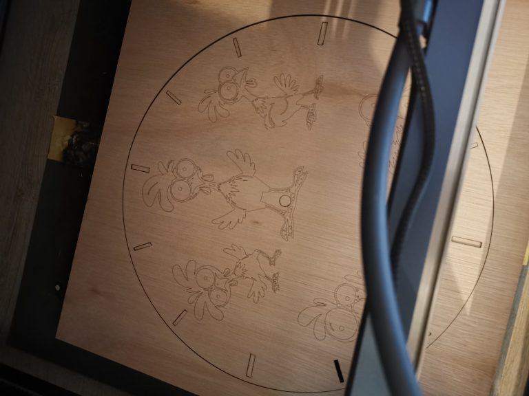 Close-up van de lasergravure op de kippenklok, net uit de lasercutter met de kabels van de machine op de voorgrond
