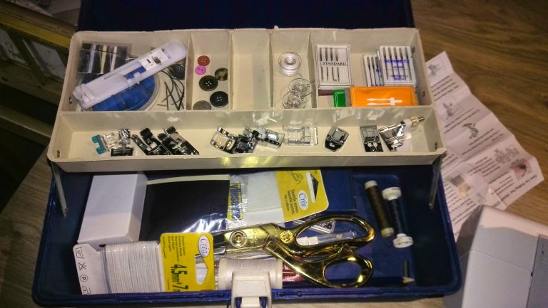 Naaikoffer met naai-accessoires: voetjes, schaar, naalden en spoelen