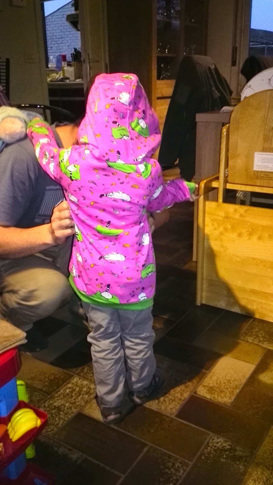 Petite fille vue de dos avec sweat rose et capuche, prête à partir