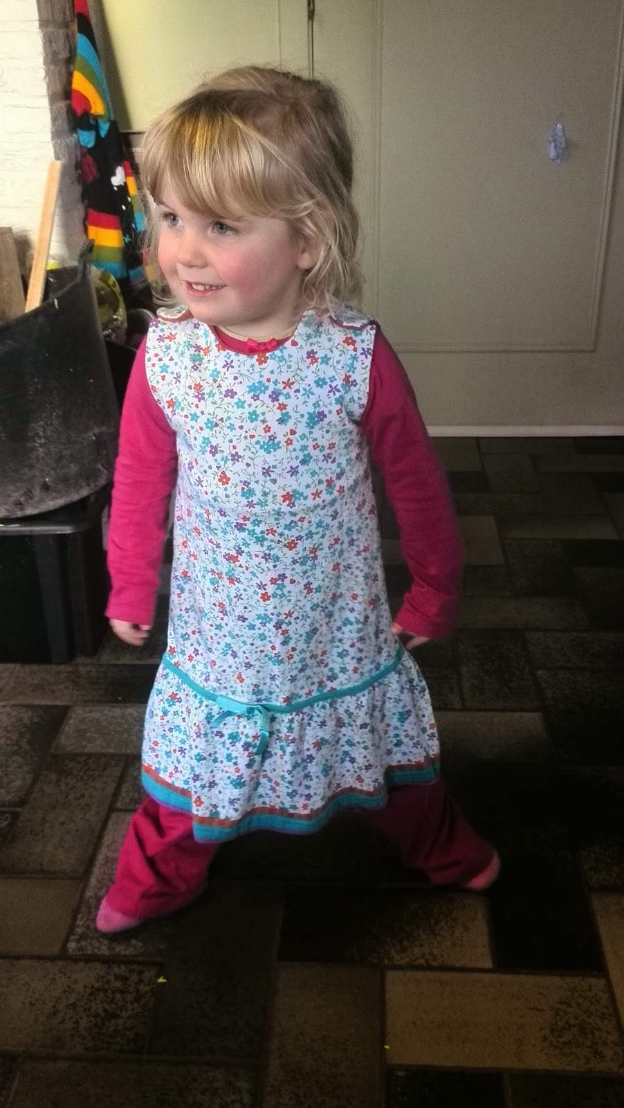 Blond meisje van 3 jaar draagt trots het zelfgemaakte bloemetjesjurkje van gerecycleerde kleren