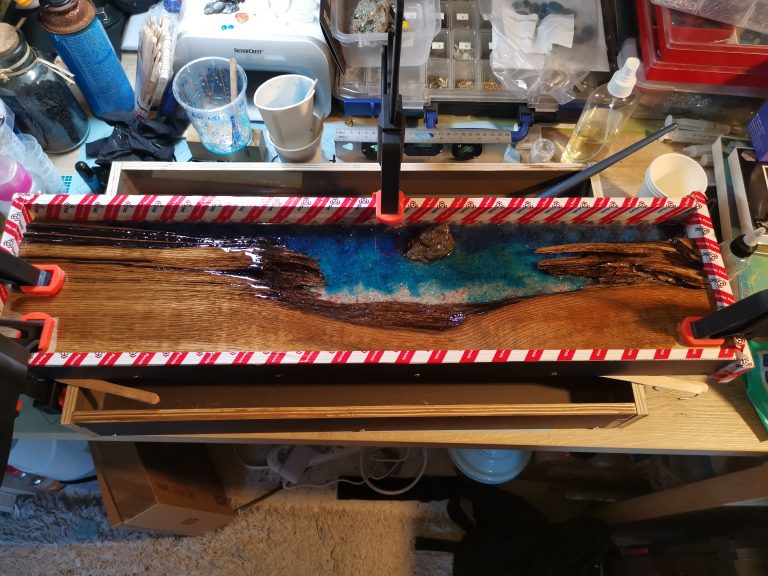 First I poured the base epoxy layer mixed with sand. Then I added blue shades to create the sea effect.